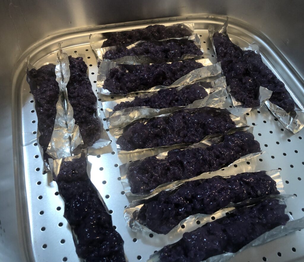 Puto Bumbong on foil packets in a steamer.