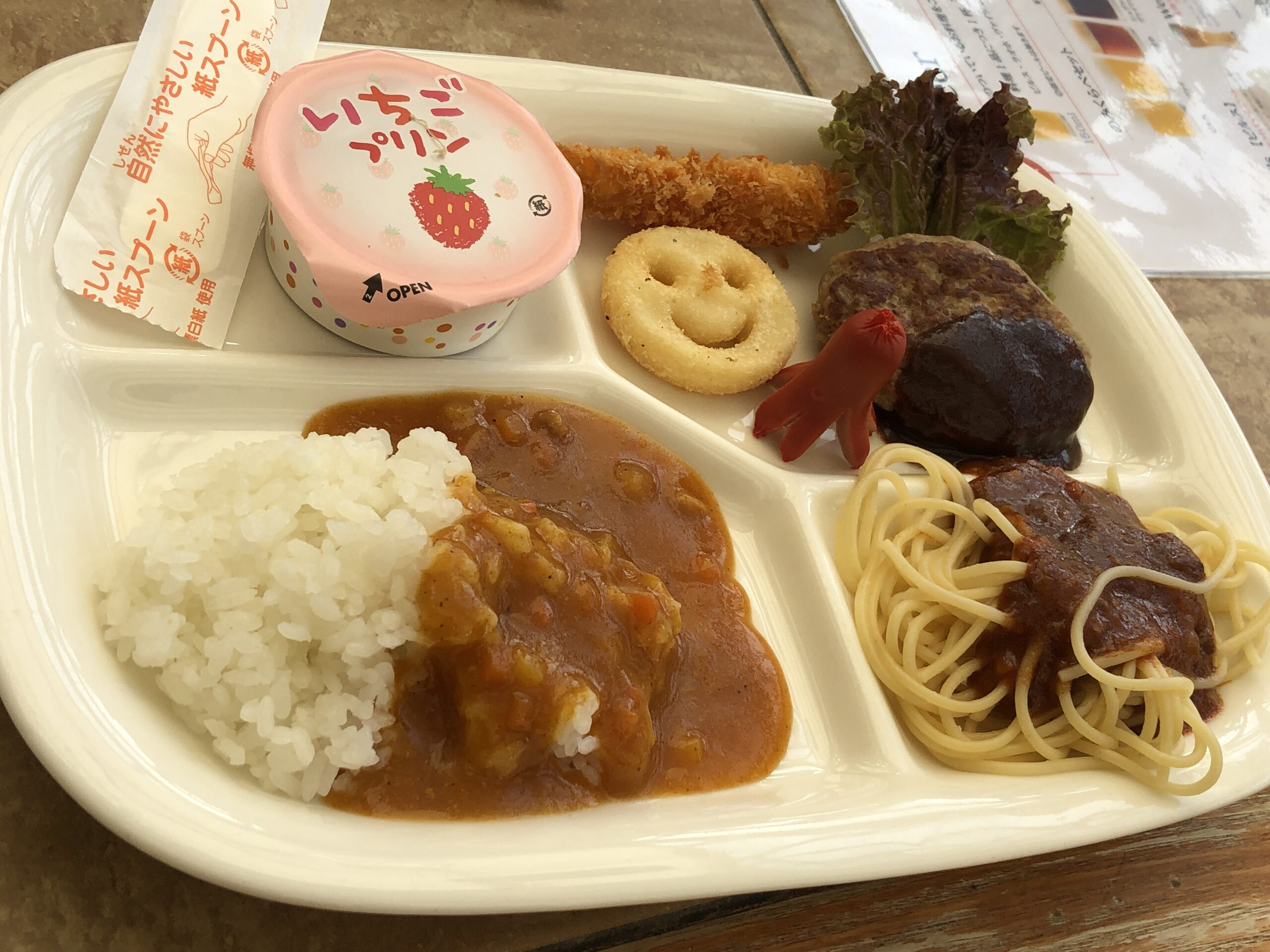 kiddie meal with with small servings of rice, curry, spaghetti, hotdog, tempura, hamburger lettuce, fries and jelly.