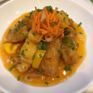 Sweet and Sour fish fillet. topped with julliened carrots and garnished with onion spring.