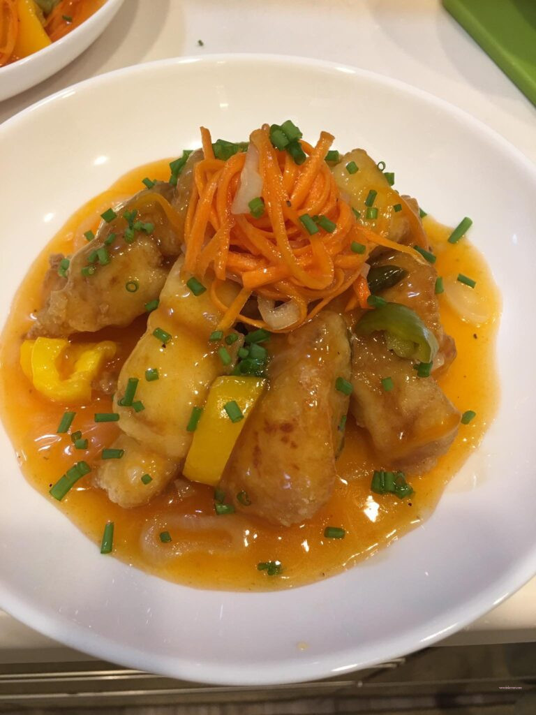 Sweet and Sour fish fillet. topped with julliened carrots and garnished with onion spring.