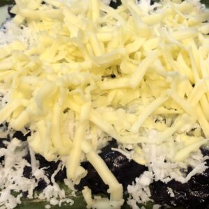 Puto Bumbong topped with grated coconut, sugar or condensed milk and cheese